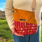 Image of orange and pink Rivet Allegro Crossbody bag with phone in pocket.