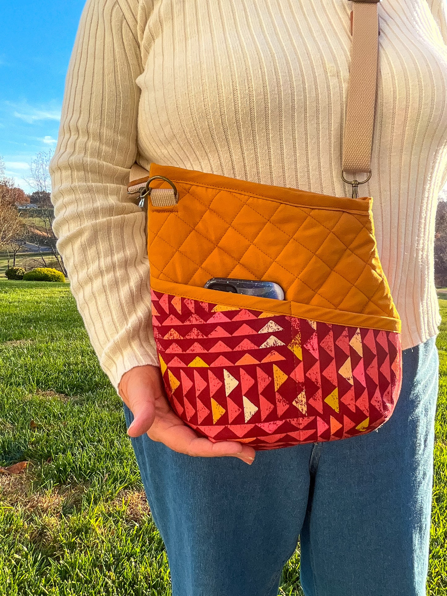 Image of orange and pink Rivet Allegro Crossbody bag with phone in pocket.